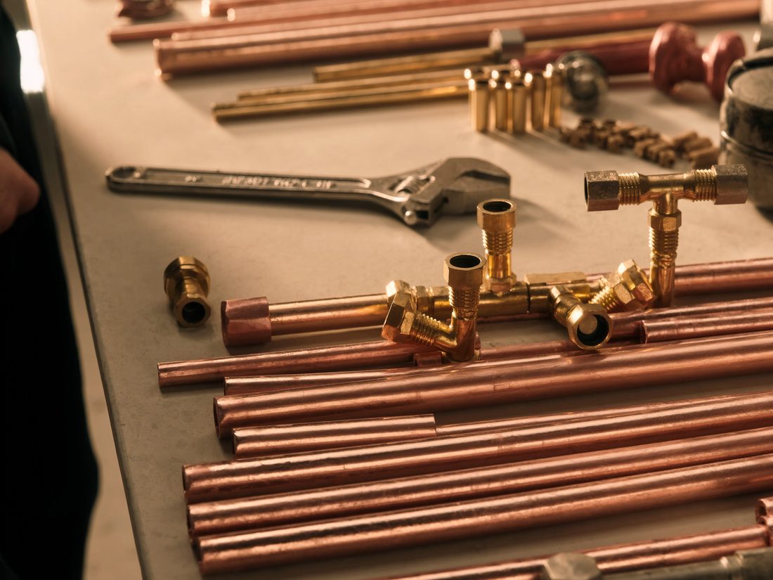 Copper pipe and brass fittings laid out on a Sugarline workbench